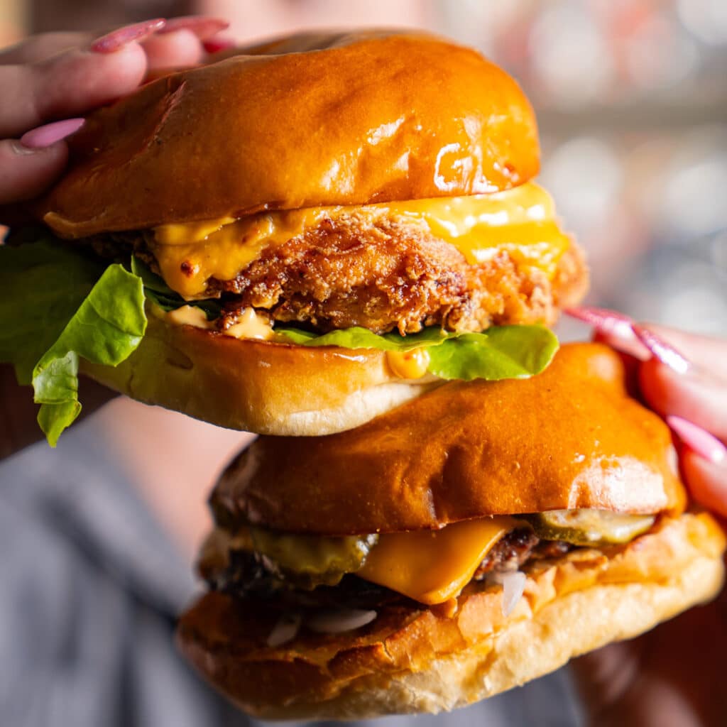 Two burgers being held in hands